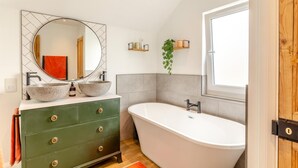 A bathroom with a freestanding bathtub, a green vanity with two sinks, a large mirror, and a window. - 4 Bed in Newquay (oc-t45967) (Newquay)