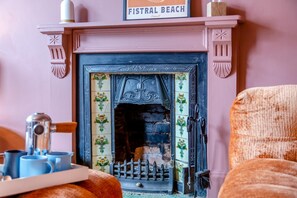 Ein gemütliches Zimmer mit Kamin, einem Tablett mit Tassen und einem Schild mit der Aufschrift 'FISTRAL BEACH'.