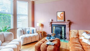 A living room with a fireplace, two sofas, a coffee table, and a lamp. - 4 Bed in Newquay (oc-t45967) (Newquay)