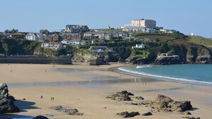 Une ville côtière dotée d’une plage de sable, de formations rocheuses et d’une colline sur laquelle se trouvent des bâtiments.