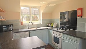 Une cuisine équipée d’un lave-vaisselle encastré, d’une cuisinière et d’une fenêtre laissant entrer la lumière naturelle.