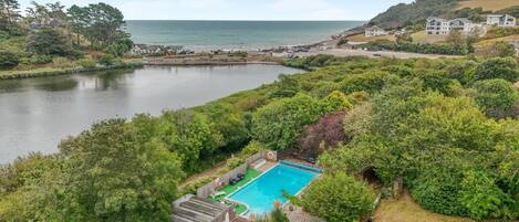 A residential area with a swimming pool, a car, and a view of the sea.