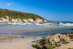 Ein Strand mit Felsen, Wellen und blauem Himmel.