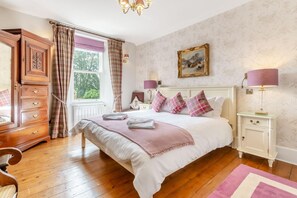 A bedroom with a large bed, bedside tables, a wardrobe, and a window with curtains. - 3 Bed in Inverarnie (oc-t45997) (Balnafoich)