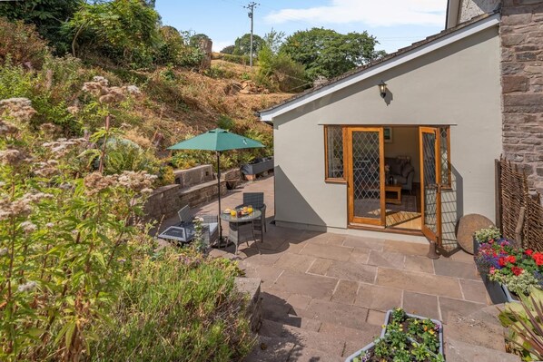 Una casa con patio, mobiliario exterior y un muro de piedra.
