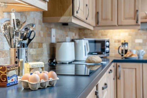 A kitchen with a microwave, toaster, and eggs on the counter.