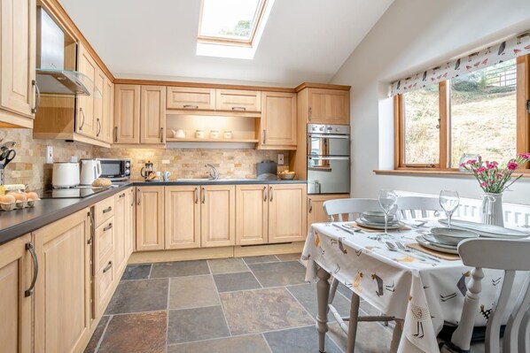 A kitchen with wooden cabinets, a built-in oven, and a dining area with a table set for two.