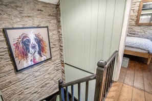 A staircase with a stone wall and a framed picture on the left. - 2 Bed in Saron (oc-l45978) (Pentre-cwrt)