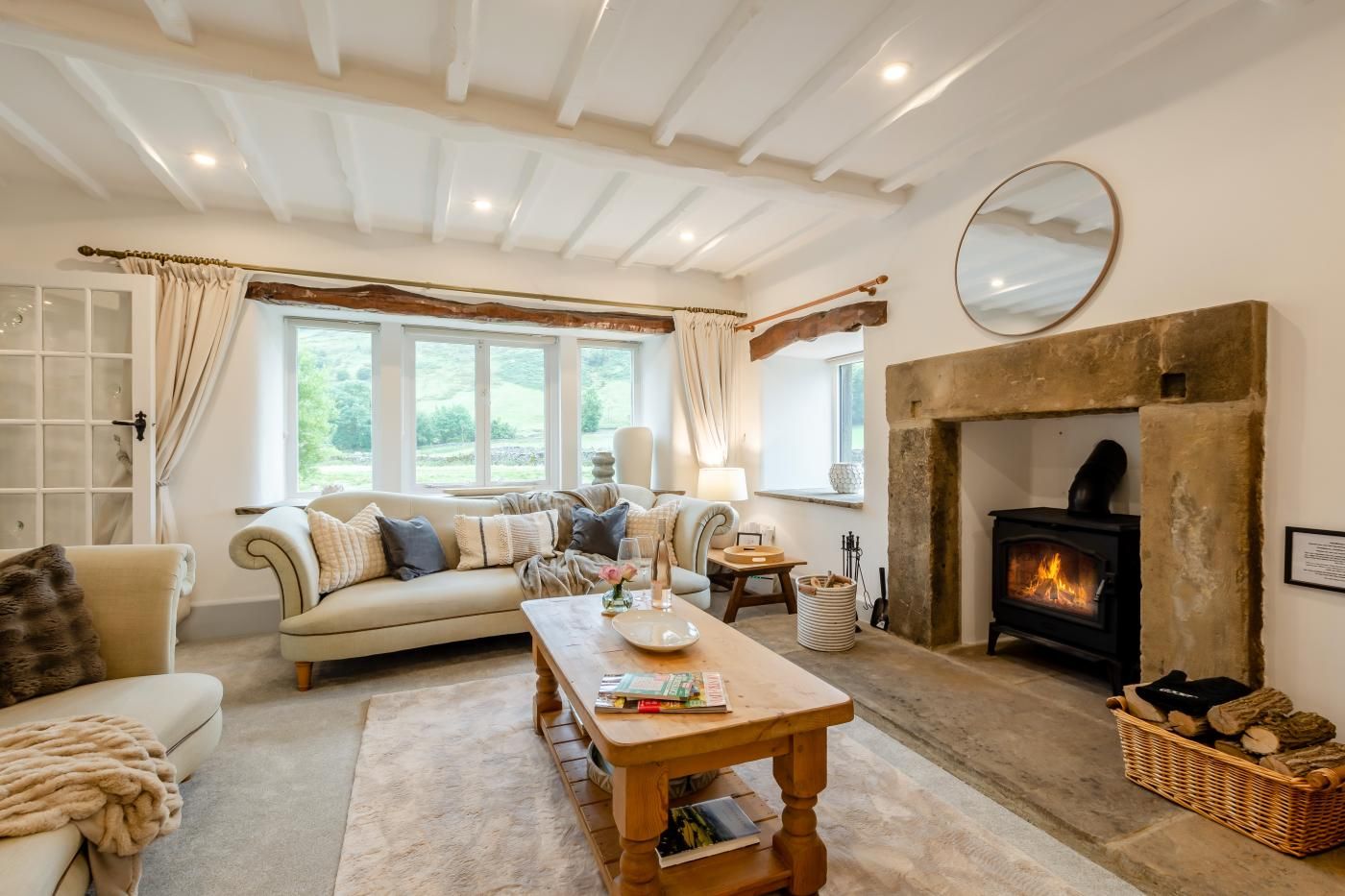 A cozy living room with a fireplace, a sofa, a coffee table, and a view of the outdoors.