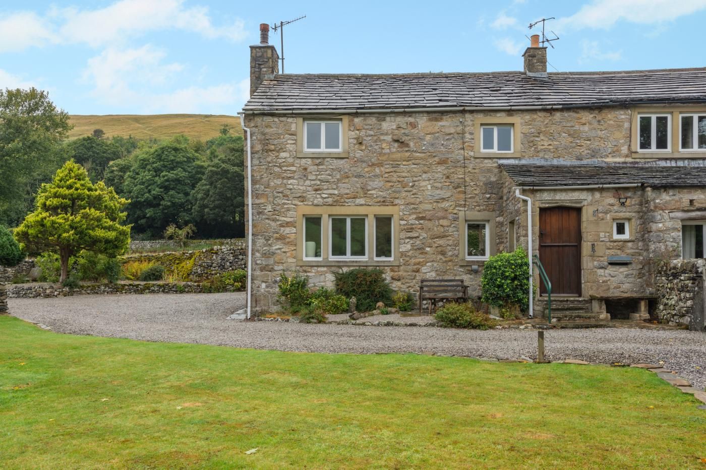 A stone house with a gravel driveway and a well-maintained lawn.