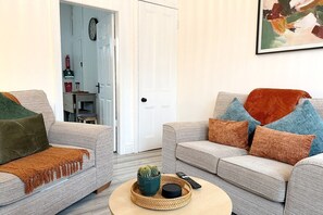 Ein Wohnzimmer mit zwei Sofas, einem Couchtisch und einer Tür zum Küchenbereich.