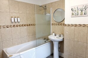Ein Badezimmer mit einer Badewanne, einer Duschkabine, einem Waschbecken und einem Spiegel.