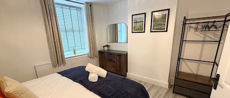 Un dormitorio con cama, cómoda, espejo y perchero.
