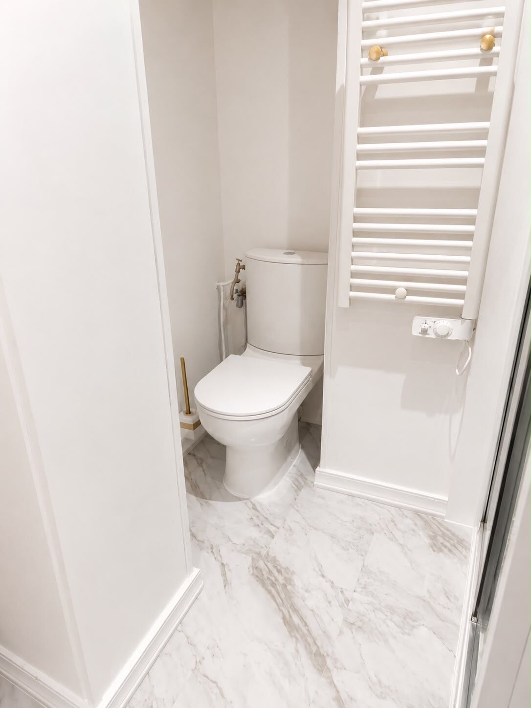 A bathroom with a toilet, a white shower enclosure, and a marble floor.