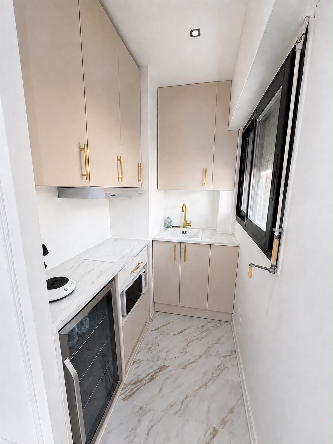 A compact kitchen with marble flooring, a built-in oven, and a window with a view.