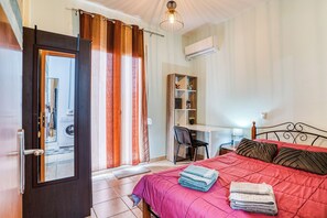 A bedroom with a bed, a desk, a chair, a wardrobe, and an air conditioning unit. - Cozy apartment in a quiet neighborhood close to Chios downtown (Chios)