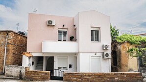 Ein zweistöckiges Wohngebäude mit Flachdach, Balkon und kleinem Garten.
