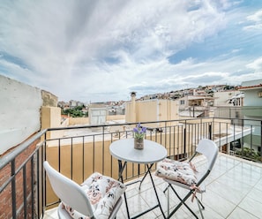 A rooftop terrace with a table and two chairs, a potted plant, and a view of the cityscape. - Cozy apartment in a quiet neighborhood close to Chios downtown (Chios)