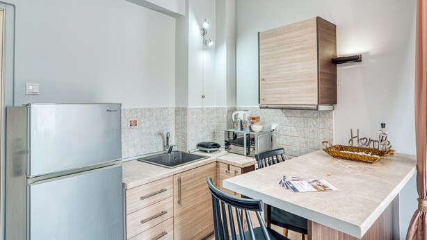 Eine kleine Küche mit Kühlschrank, Spüle und Holzschränken.