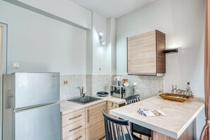 Una cocina pequeña con refrigerador, lavamanos y gabinetes de madera.