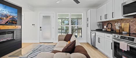 Un salon moderne avec un canapé, un téléviseur à écran plat, une cheminée et un ventilateur de plafond.