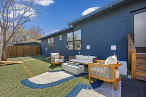 Ein Garten mit einem blauen Haus, Gartenmöbeln und einer kleinen Terrasse.