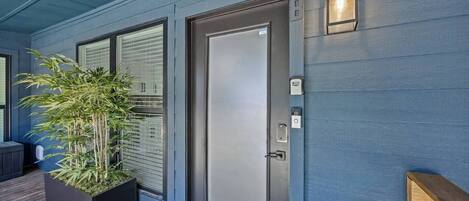 A modern exterior with a blue door, a potted plant, and a wooden deck.