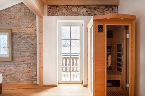A room with a brick wall, a wooden sauna, and a door leading outside. - "Sleeping Witch" Vacation Rental, 74 square meters (Schönau am Königssee)