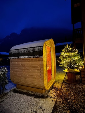 A small, wooden cabin with a snow-covered roof, a lit interior, and a Christmas tree outside. - "Sleeping Witch" Vacation Rental, 74 square meters (Schönau am Königssee)