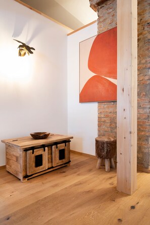 Una mesa de madera rústica con un cuenco, una lámpara de pared y un cuadro abstracto grande.