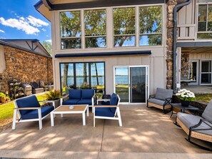 Un patio extérieur moderne avec un mur en pierre, un espace barbecue couvert et un coin salon avec une table et des chaises.