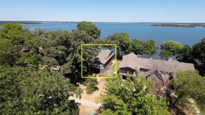 A residential property with a large house surrounded by dense trees and a lake in the background. - Updated Large Lakefront Townhouse with Bald Eagle Views overlooking Grand Lake. (Afton)