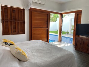 Ein Schlafzimmer mit Bett, Fernseher und Blick auf einen Swimmingpool.