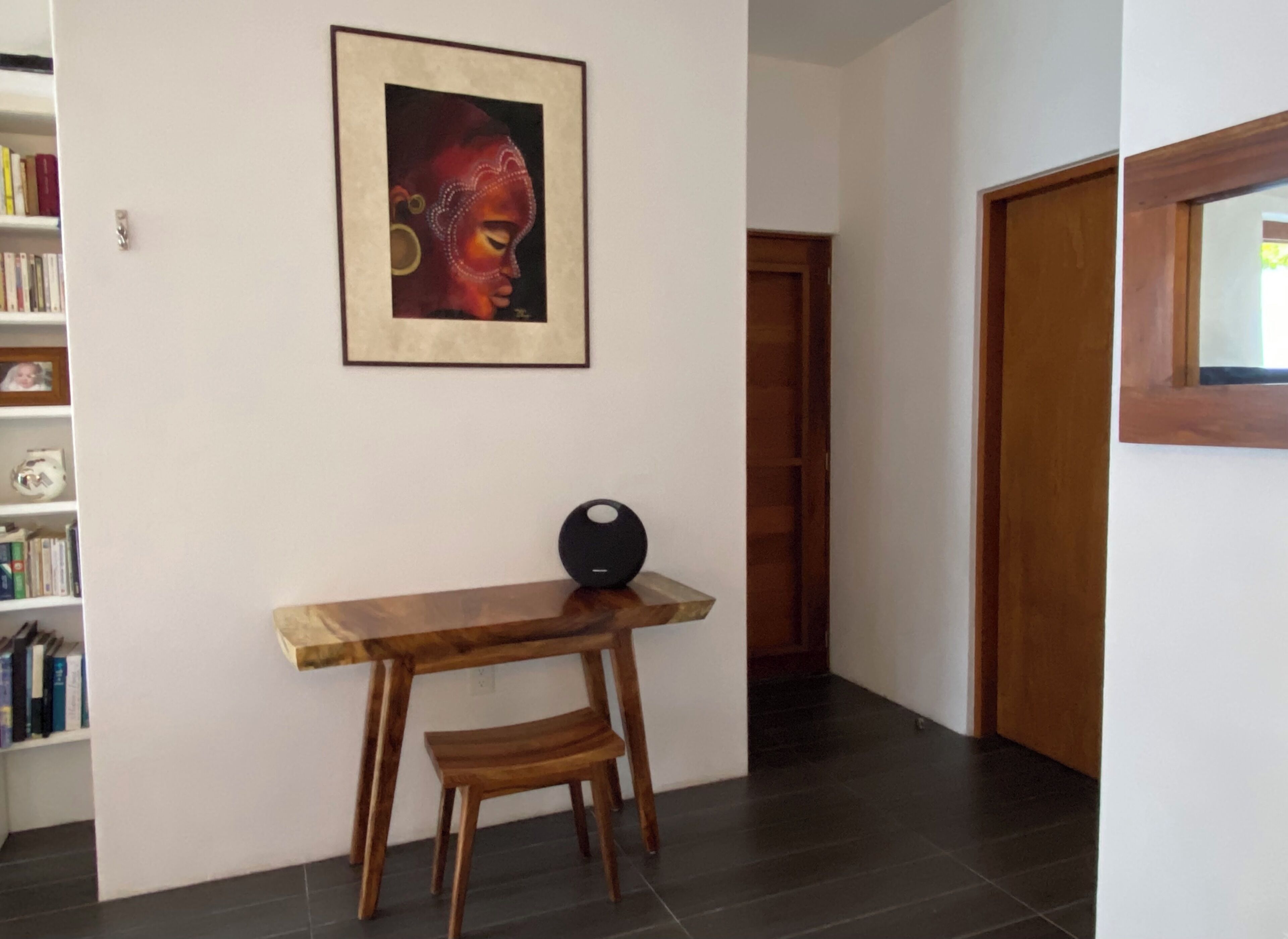 Une pièce avec une table et un banc en bois, une œuvre d’art encadrée au mur et une bibliothèque remplie de livres.