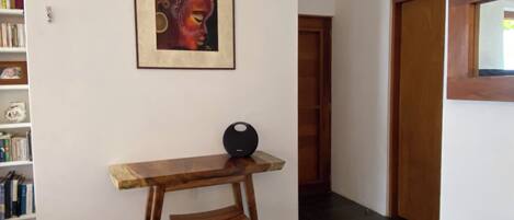 A room with a wooden table and bench, a framed artwork on the wall, and a bookshelf with books.