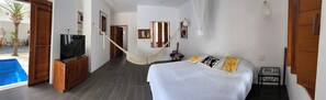 A hotel room with a bed, a TV, a small table, and a view of an outdoor swimming pool. - CENTRAL PRIVATE HOME WITH PRIVATE POOL, 3 BLOCKS FROM THE MALECON (Cozumel)
