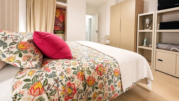 A bedroom with a bed, a wardrobe, a television, and a shelf with items. - Castle Comfort (Los Cristianos)