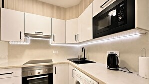 A modern kitchen with built-in appliances, including a microwave, oven, and dishwasher. - Castle Comfort (Los Cristianos)