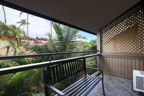 A balcony with a metal railing, a bench, and an air conditioning unit. - Tropical Garden Vibes Maui (Kihei)