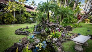 A tropical garden with a pond, rocks, and a stone bench. - Tropical Garden Vibes Maui (Kihei)