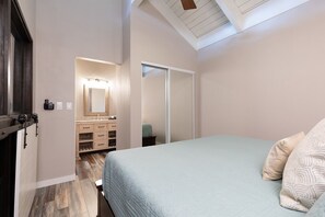 Een slaapkamer met een bed, een dressoir, een spiegel en een plafond met dakramen.