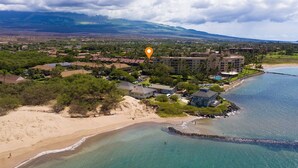 A coastal resort with beachfront properties, a large building complex, and a view of distant mountains. - Tropical Garden Vibes Maui (Kihei)