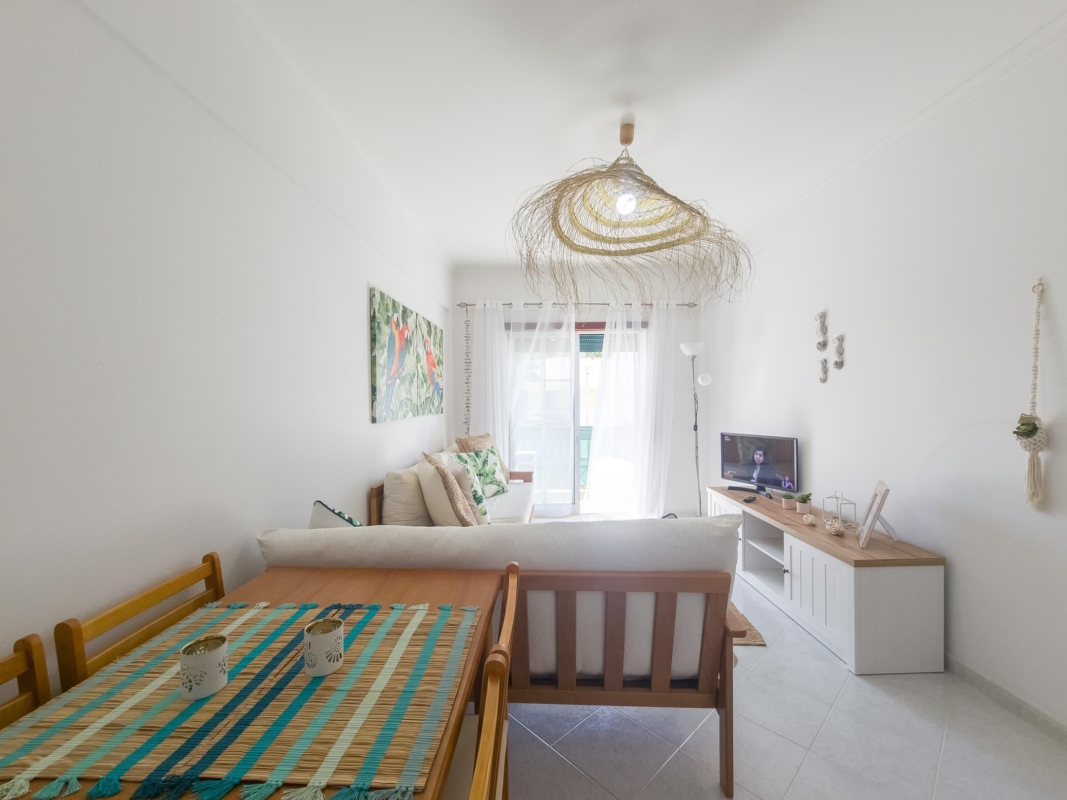 Ein modernes Wohnzimmer mit Essbereich, Fernseher und einer dekorativen Deckenleuchte.