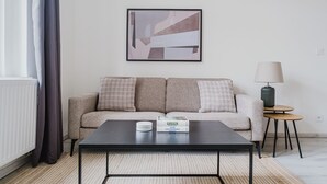 En moderne stue med sofa, sofabord, lampe og et indrammet abstrakt billede.