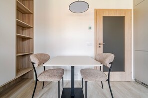 A room with a white table, four chairs, a wooden bookshelf, a door, and a light fixture. - Blueground | Nusle, view, furnished nr Vysehrad (PRG-70) (Prague)