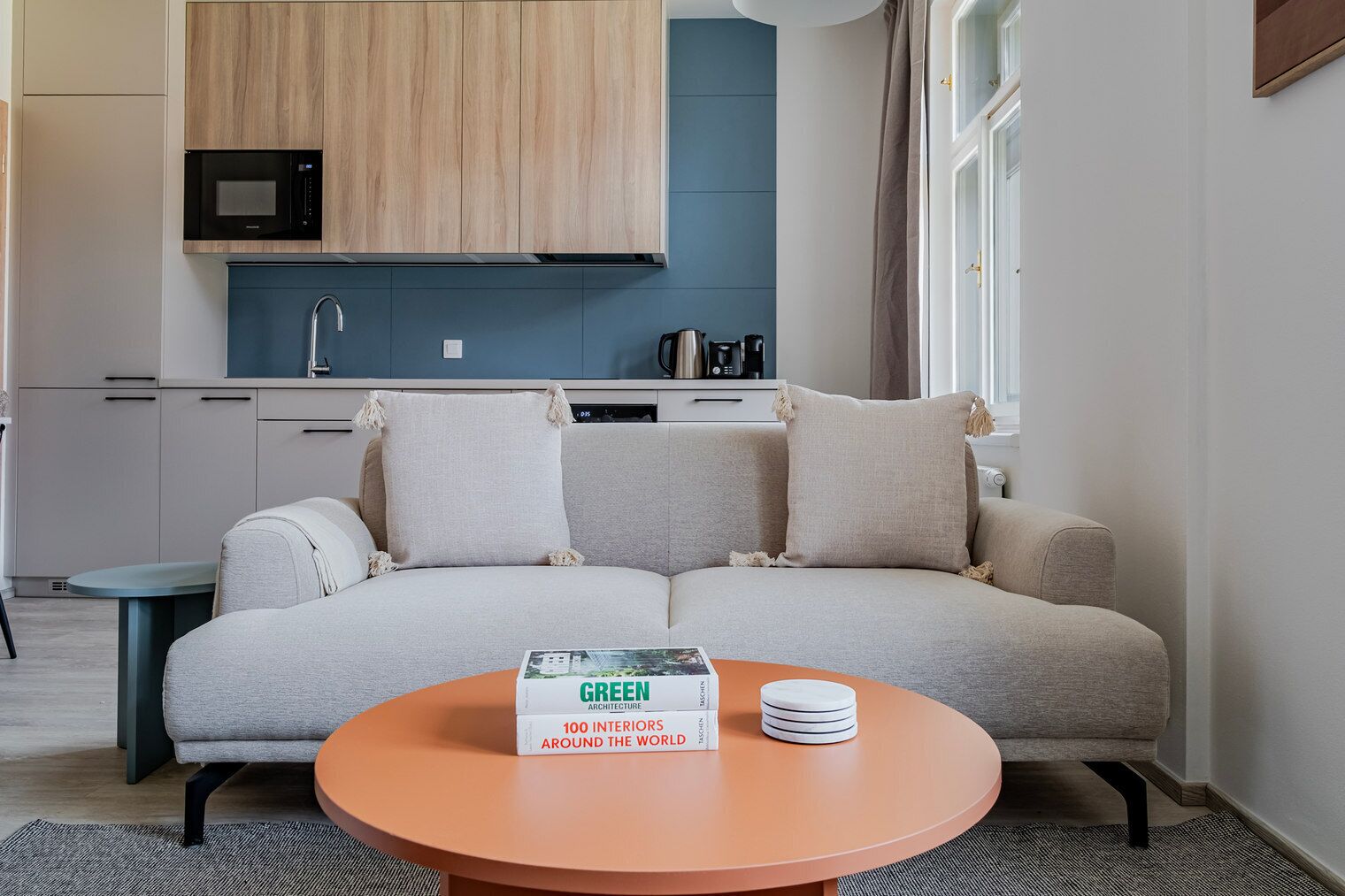 Ein modernes Wohnzimmer mit einer Couch, einem Couchtisch und einem Buch mit dem Titel 'GREEN ARCHITECTURE 100 INTERIORS AROUND THE WORLD'.