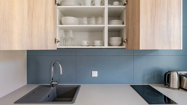 A modern kitchen with a built-in sink, stainless steel kettle, and a range hood. - Blueground | Nusle, view, furnished nr Vysehrad (PRG-70) (Prague)