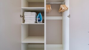 A wardrobe with shelves and hanging space, containing folded towels and an iron. - Blueground | Nusle, view, furnished nr Vysehrad (PRG-70) (Prague)