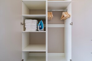 A wardrobe with shelves and hanging space, containing folded towels and an iron. - Blueground | Nusle, view, furnished nr Vysehrad (PRG-70) (Prague)