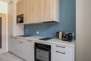 Une cuisine moderne avec des meubles blancs, une bouilloire en acier inoxydable, un grille-pain et un lave-vaisselle.